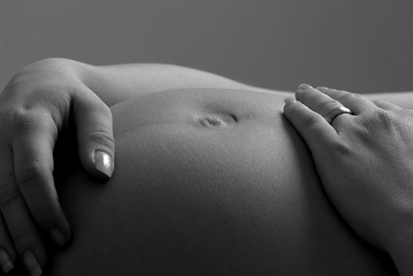 babybauch liegend mit händen, aktfotografie in schwarz-weiss