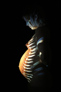 babybauch durch diaprojektion beleuchtet, schwangerschaftsfoto in farbe
