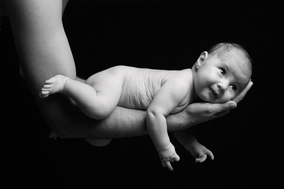 babyfoto in schwarz-weiss, kleines baby liegt auf dem unterarm seines vaters