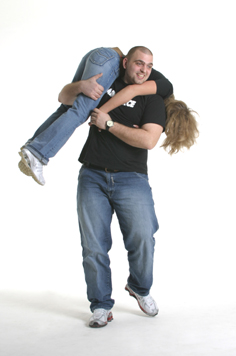 mann trägt frau über der schulter, fotograf münchen, beide in jeans im fotostudio mit weissem hintergrund