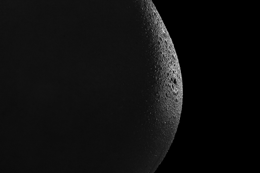 ein babybauch wie ein vollmond, schwarz-weiss, low key photographie, schwangerschaftsfoto nahaufnahme